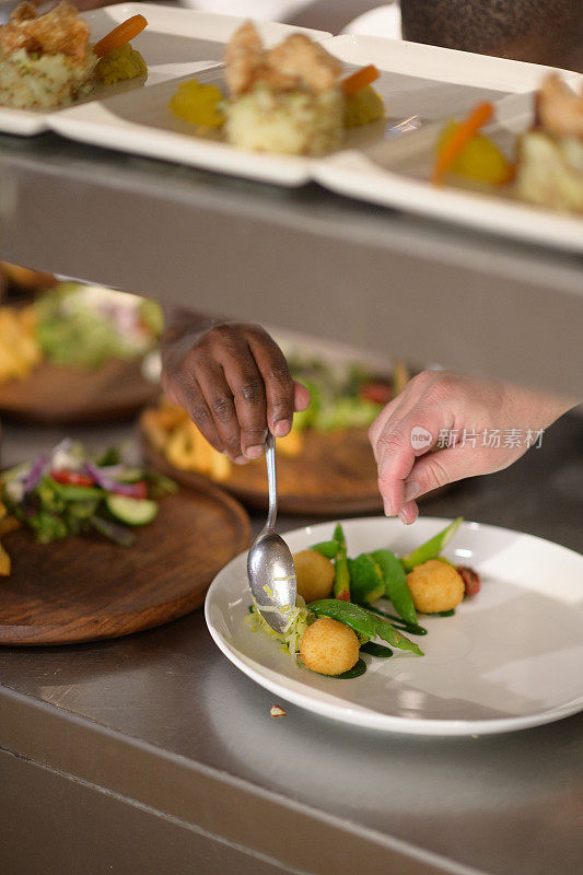 非洲和高加索厨师的手准备盘子蔬菜在厨房柜台上