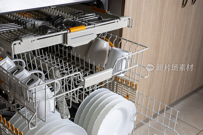 从开放式内置洗碗机中抽出三个抽屉。厨房配有集成电器。把洗碗机里的盘子洗干净。