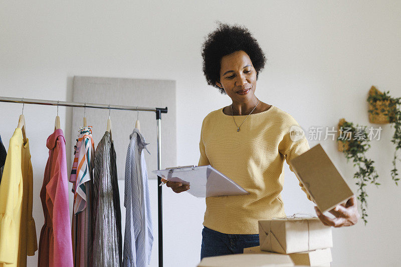 有吸引力的女商人检查订单和包装衣服在纸板箱