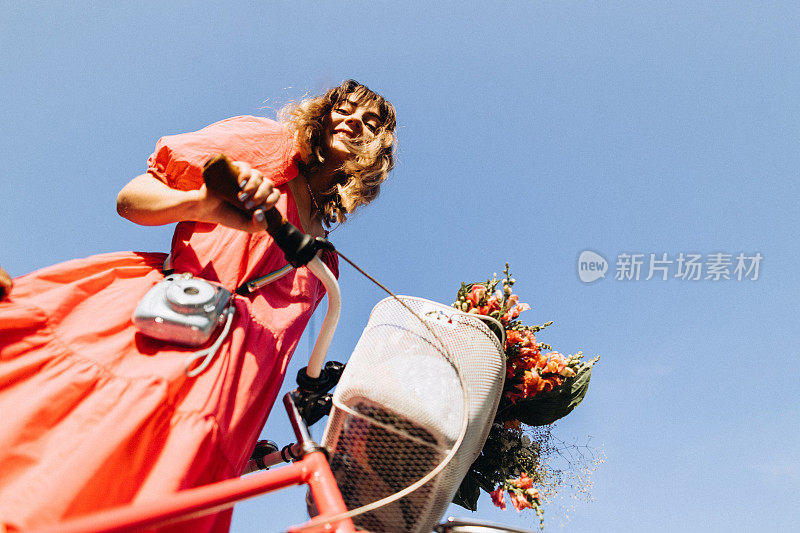 开朗的女人骑着她的复古自行车，Instax相机以蓝天为背景