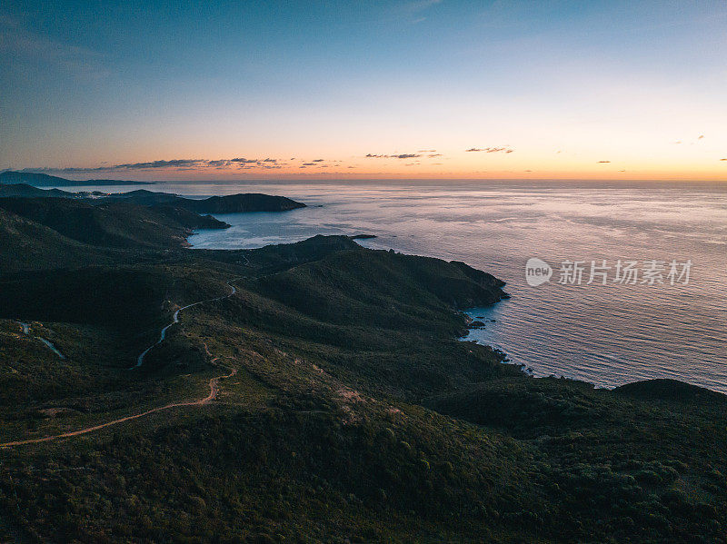 日出在崎岖的海岸线和宁静的大海上