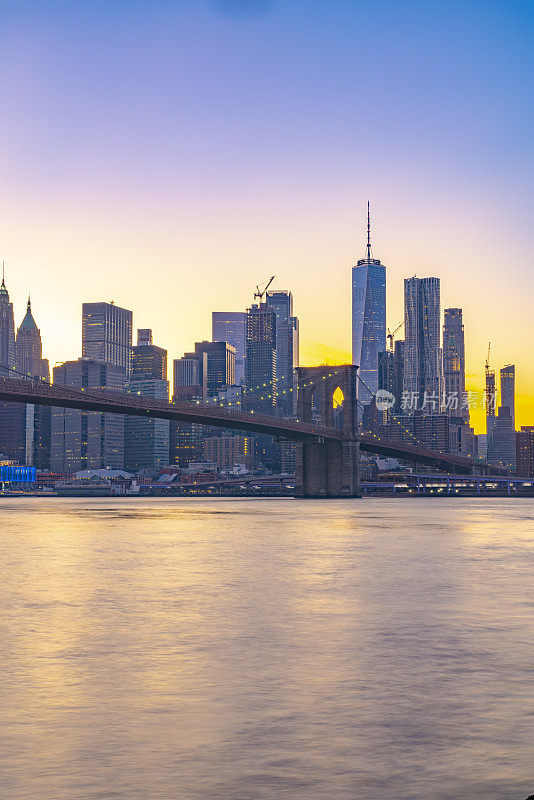 日落时分，从布鲁克林俯瞰布鲁克林大桥、世界贸易中心一号大楼、曼哈顿市中心和摩天大楼。