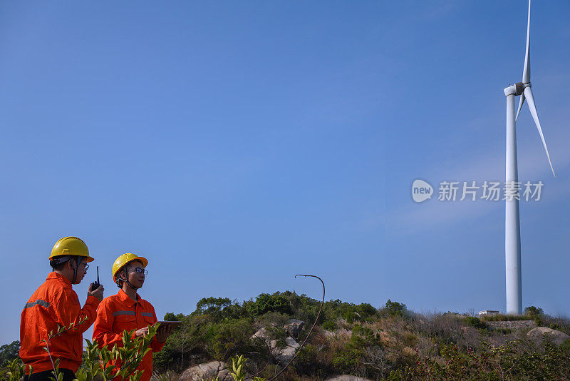 在乡村风景中，工人们在风力涡轮机旁交谈