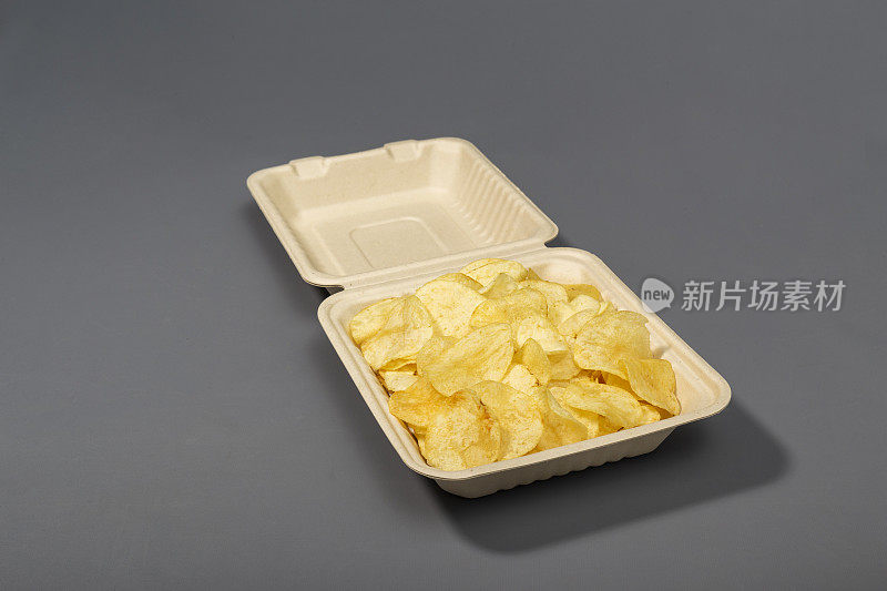 用灰色背景的硬纸板外卖包装取出薯片