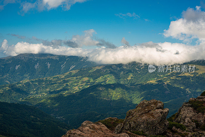 在一个阳光明媚的夏日里，有美丽的山峦和岩石景观。