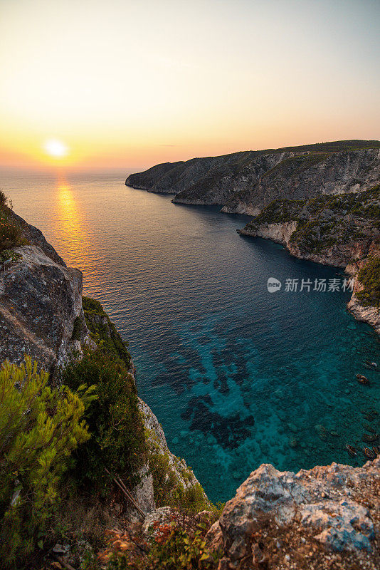 在夏天日落时分，海湾有清澈的水和岩石悬崖的美丽景色