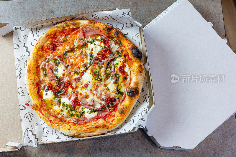 圆烤火腿和奶酪披萨在开放的披萨盒