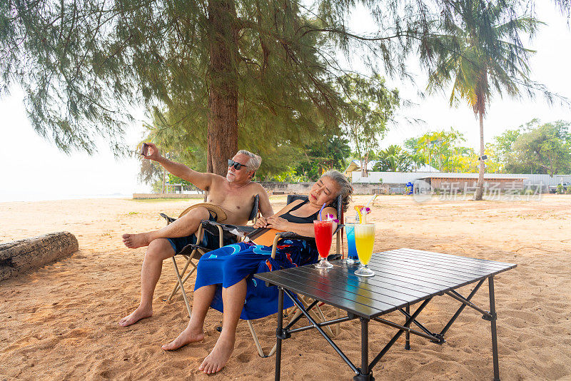 阳光明媚的日子里，一对亚洲老年夫妇一起在海滩上休息。