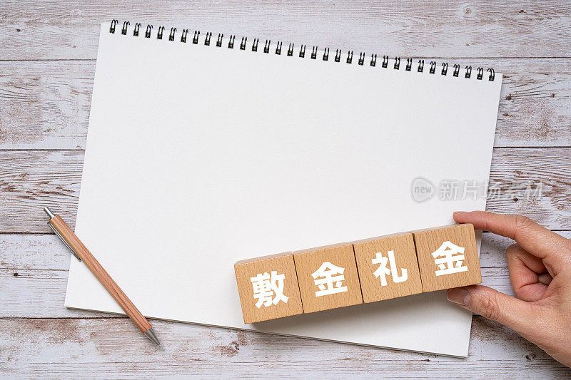 带有“shikikinreikin”概念文字的木块，一支笔和一个笔记本。