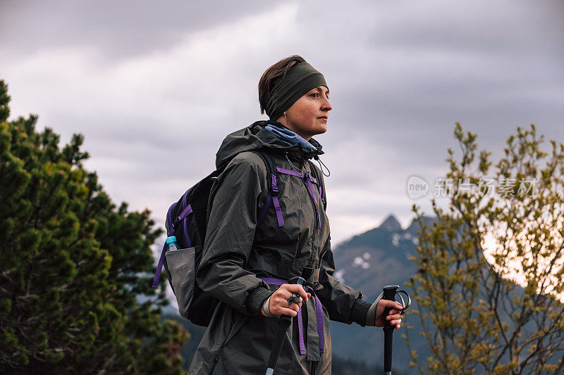 女人的女性肖像，谁在山中旅行。穿着保暖运动服在户外徒步旅行的人。生活方式摄影的人物和北欧徒步，旅游的概念。女孩是背包客，背包里装着旅游装备。