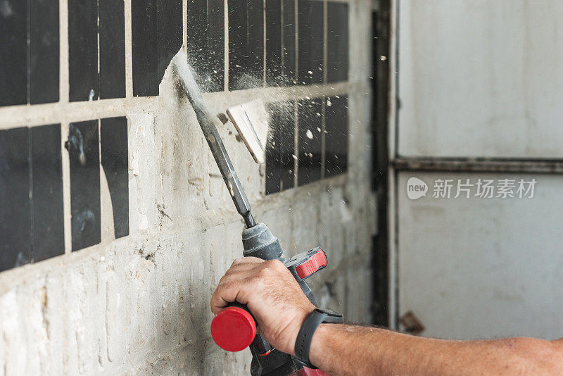建筑工用打孔机拆除混凝土墙上的旧瓷砖