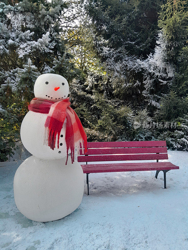 雪人站在红长凳旁边。地上的雪