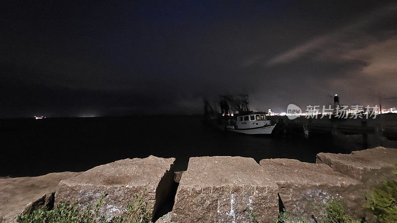 渔船停靠在夜晚，背景是岛上的灯光