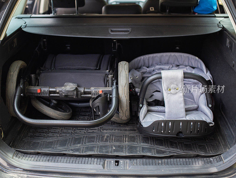 把婴儿车折叠起来放在汽车后备箱里搬运，特写