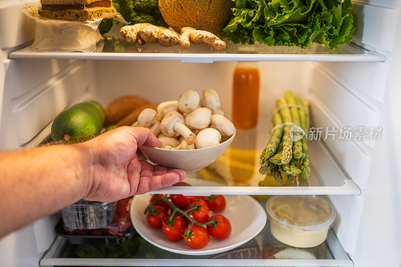 手从冰箱里拿出一碗蘑菇