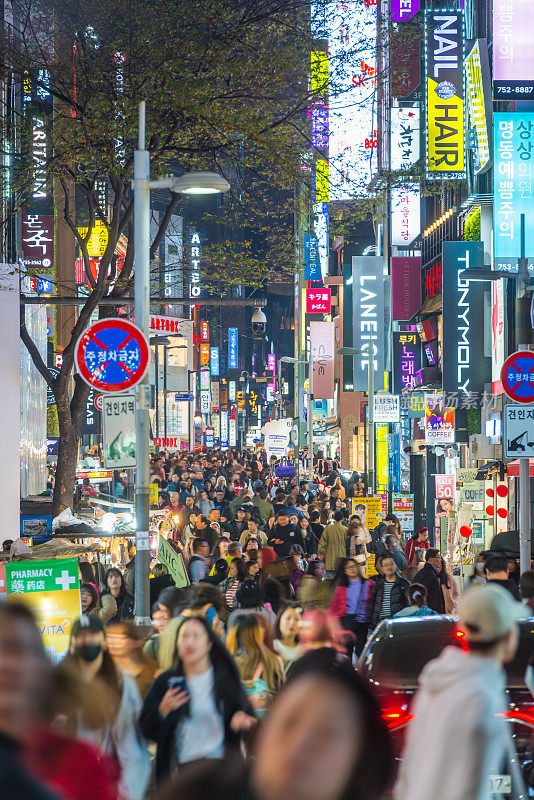 夜晚，韩国繁忙的街道上熙熙攘攘的购物者