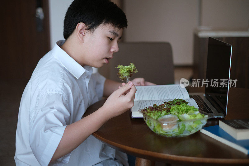 吃健康蔬菜沙拉的亚洲少年