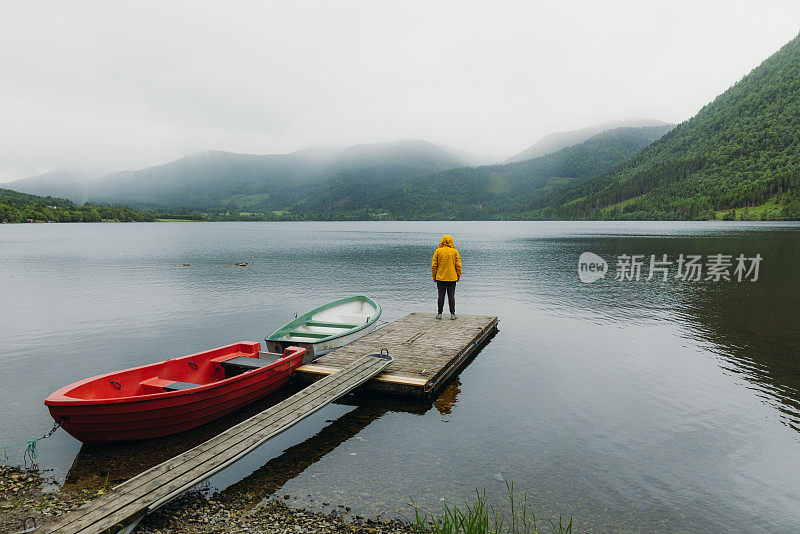 身穿黄色夹克的男子在挪威的湖边沉思着夏日的早晨