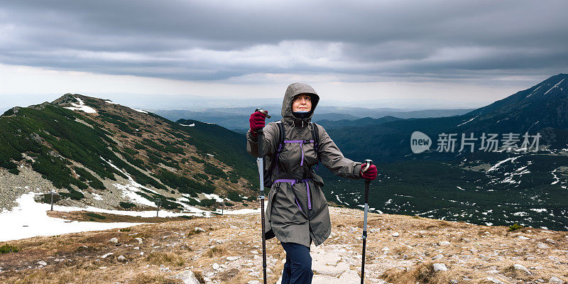 女孩是背包客，背包里装着旅游装备。女人的女性肖像，谁在山中旅行。穿着保暖运动服在户外徒步旅行的人。生活方式摄影的人物和北欧徒步，旅游的概念。