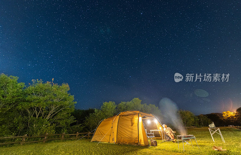 一位妇女正在露营，欣赏夜空中的星星