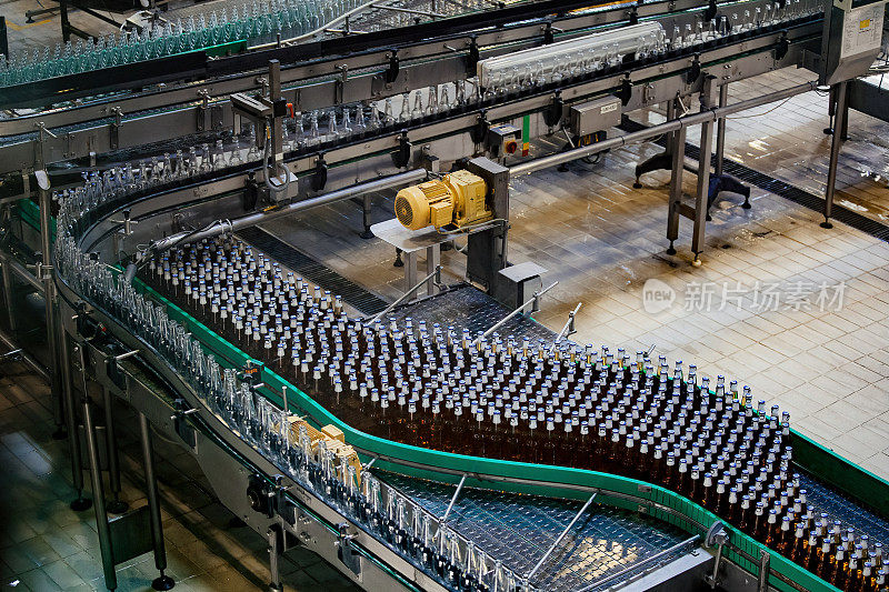 现代化自动化啤酒装瓶生产线。传送带上移动的啤酒瓶