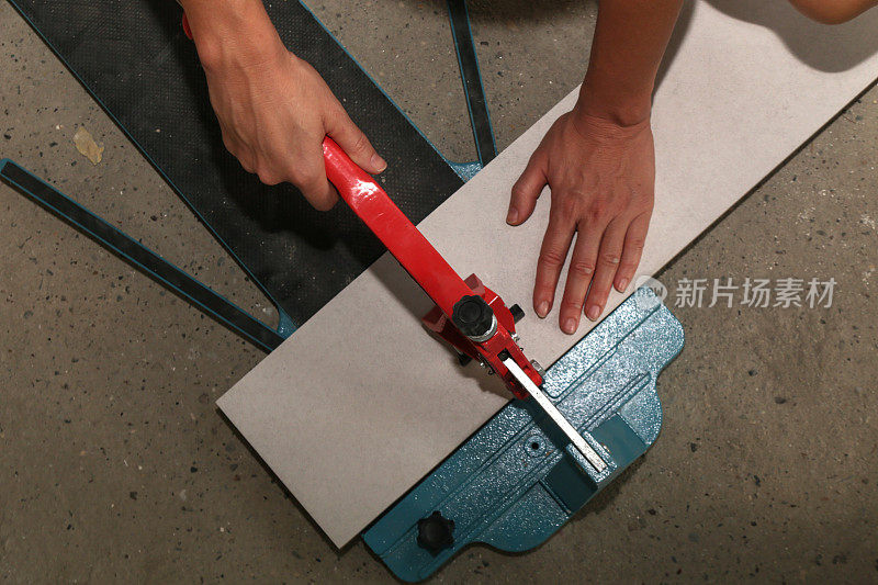 使用标准的手动瓷砖切割机切割瓷砖。瓷砖在浴室中逐步安装的过程。DIY家居装修。
