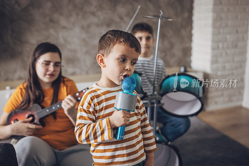 当其他孩子在演奏乐器时，一个男孩对着麦克风唱歌