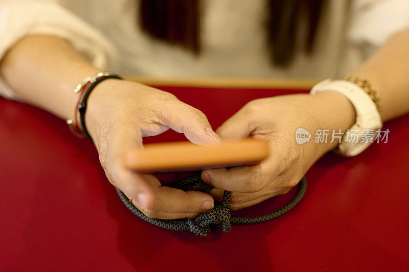 一位亚洲年轻女性用手指在智能手机上发短信。