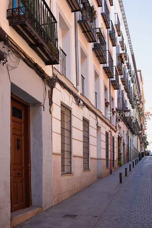 外立面有许多窗户，阳台，门。西班牙，马德里，市中心的老房子墙，古老的街道门