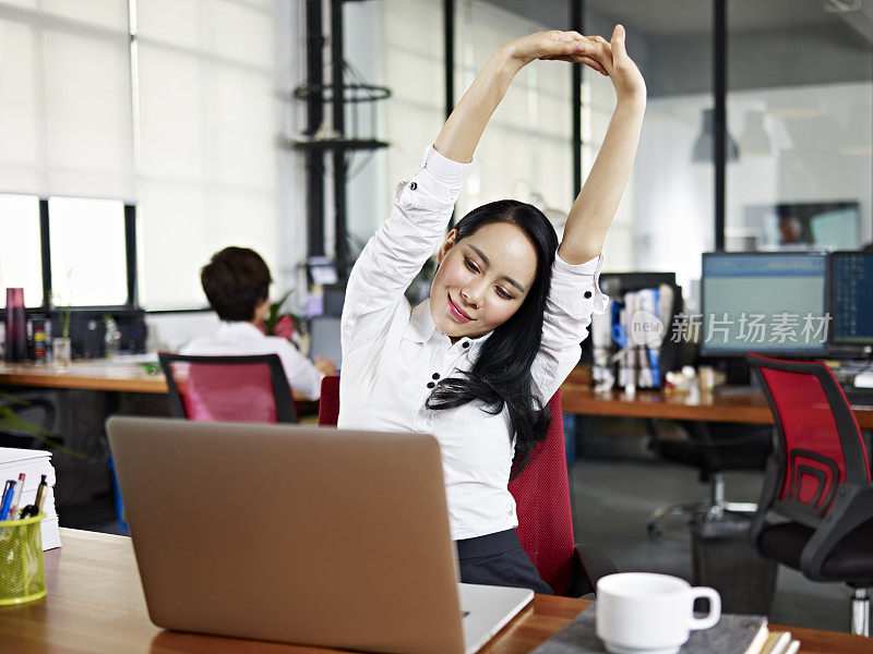 亚洲商业女性在办公室伸展手臂