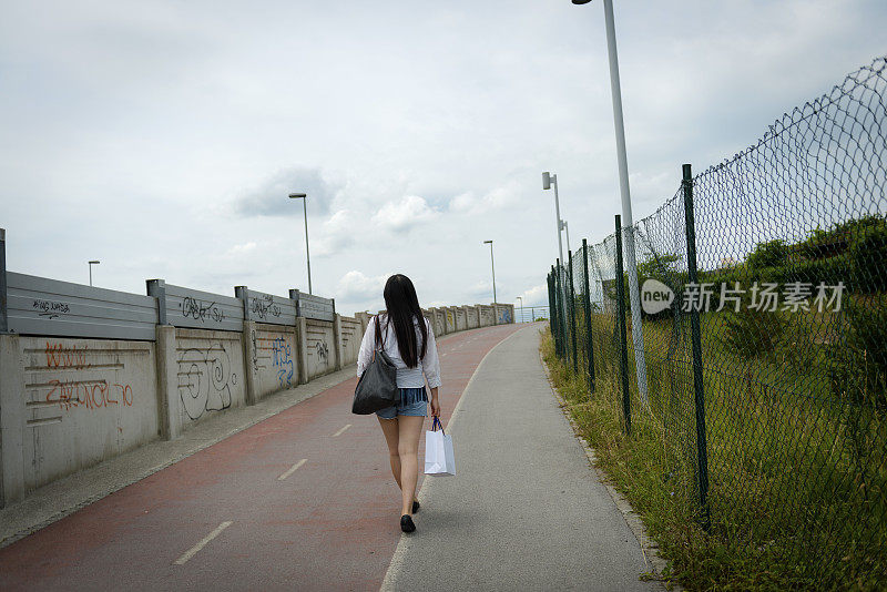 购物后走在自行车道上的年轻中国妇女