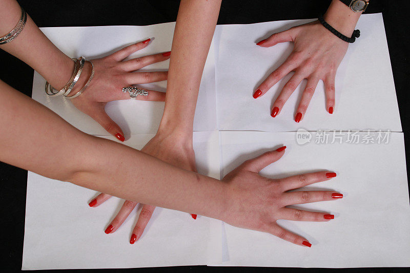 四个女人的手放在白纸上
