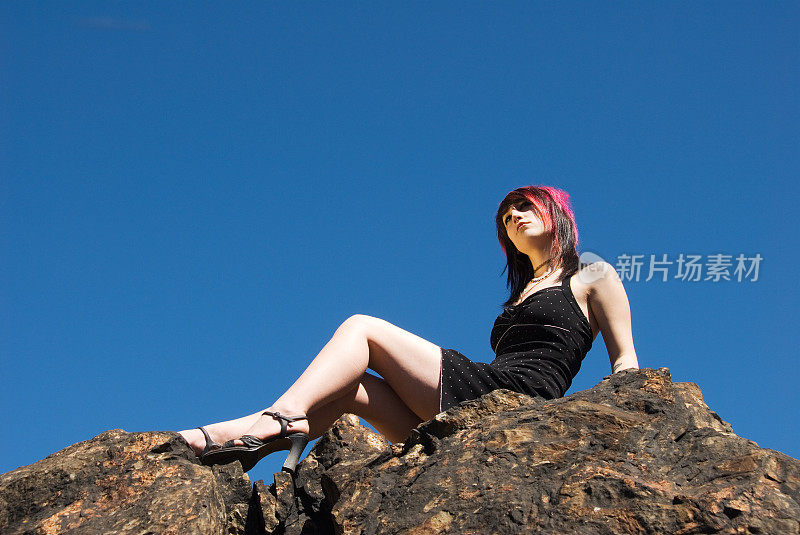 美丽的年轻女子坐在岩石上