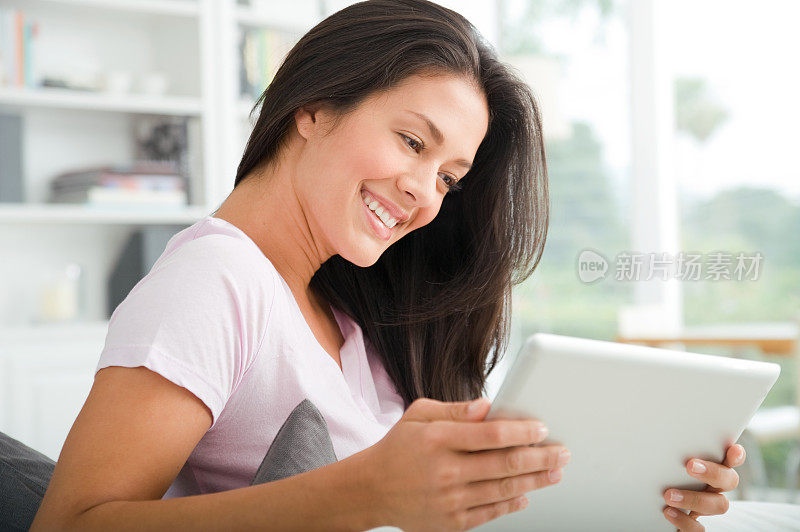 一位女性手拿平板电脑，面带微笑