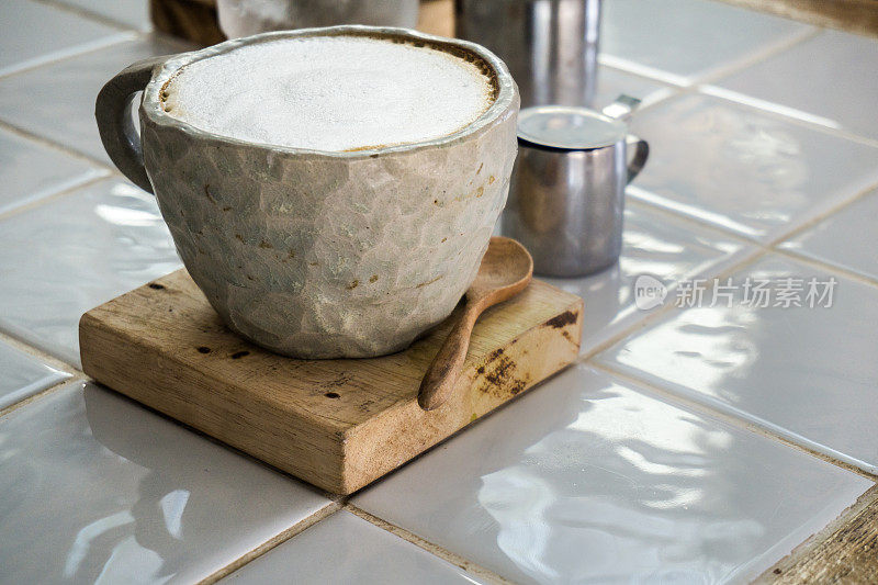 热咖啡装在质朴的杯子里，放在木板上。