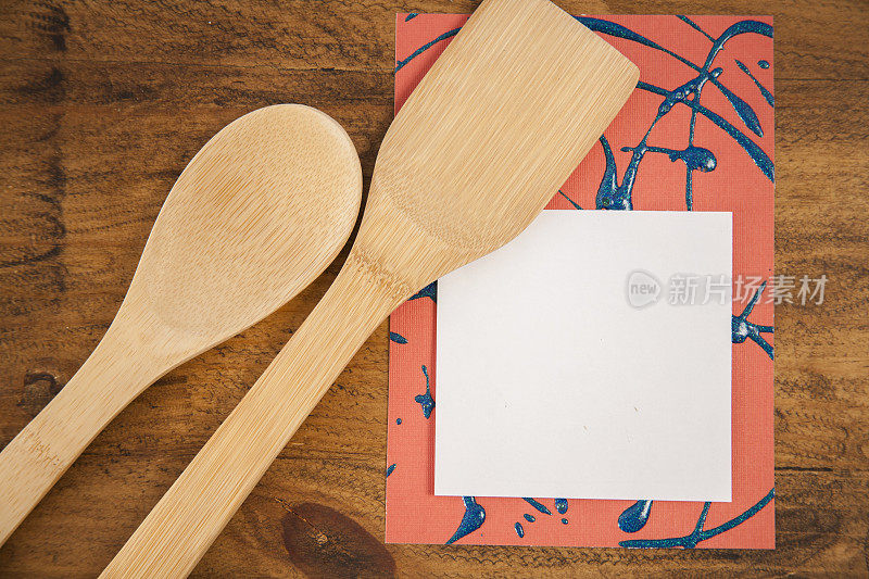 木桌上放着空白记事本的厨房用具。