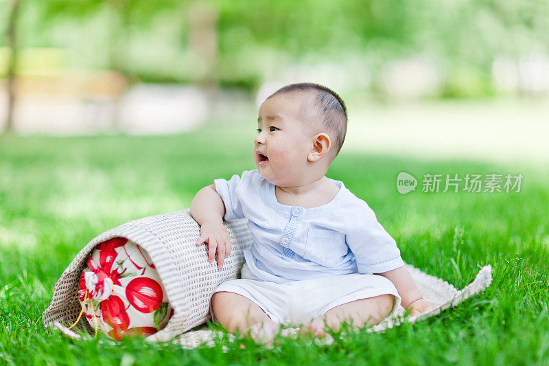 可爱的亚洲小男孩坐在草坪上