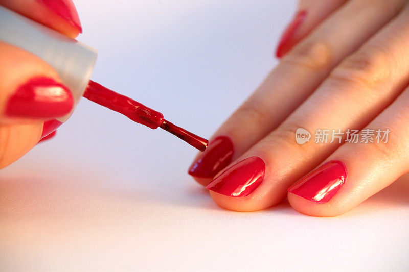 女孩在指甲上涂红色指甲油的特写