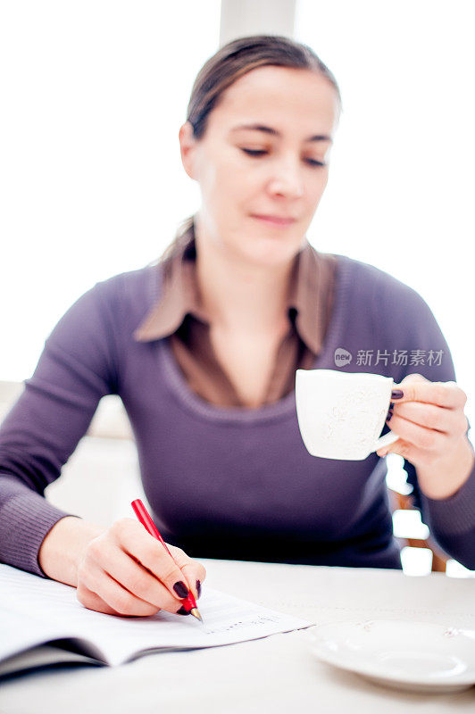 年轻女子在写音符的时候喝咖啡休息-双手合十