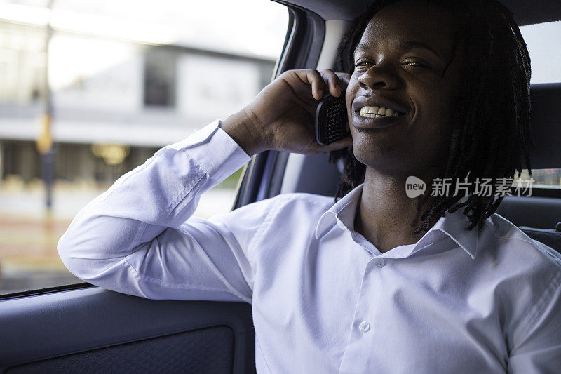 一个非洲商人坐在车里讲电话