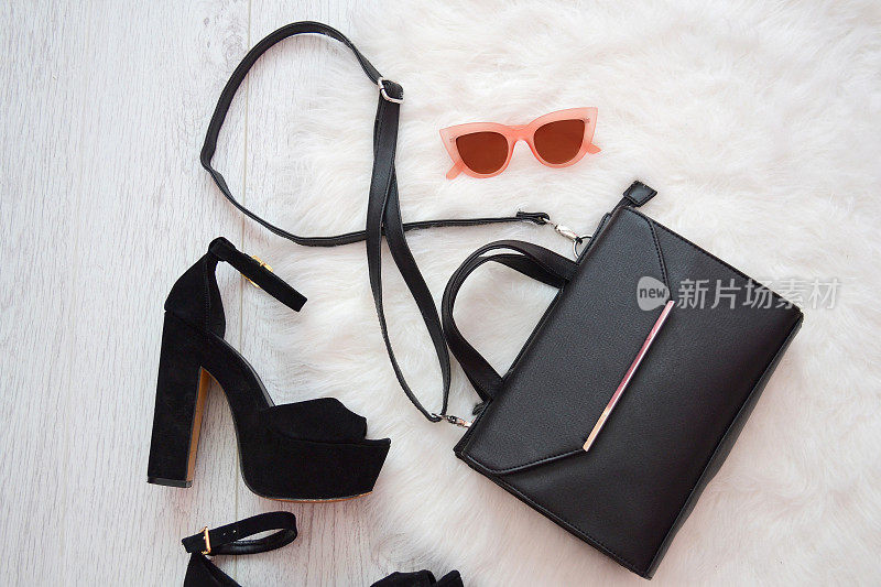 时尚的概念。黑色的手提包，白色的鞋子和粉色的眼镜。俯视图