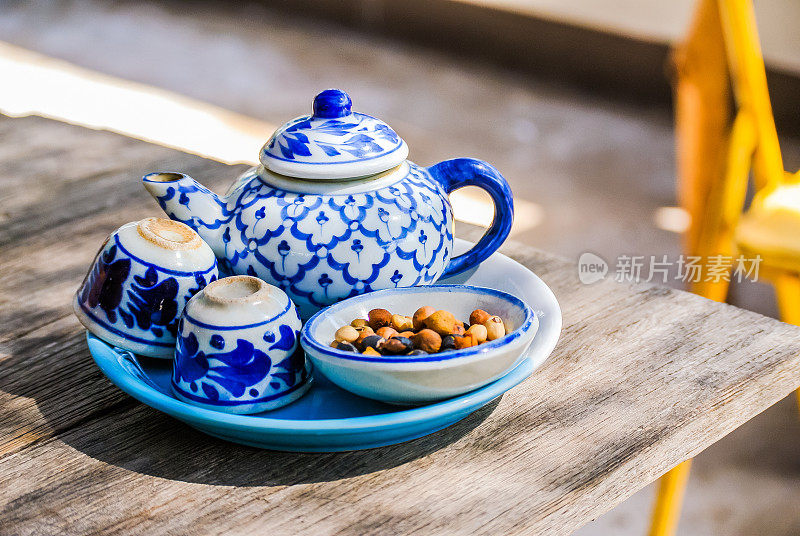 木桌上放着陶瓷茶壶、茶杯和点心