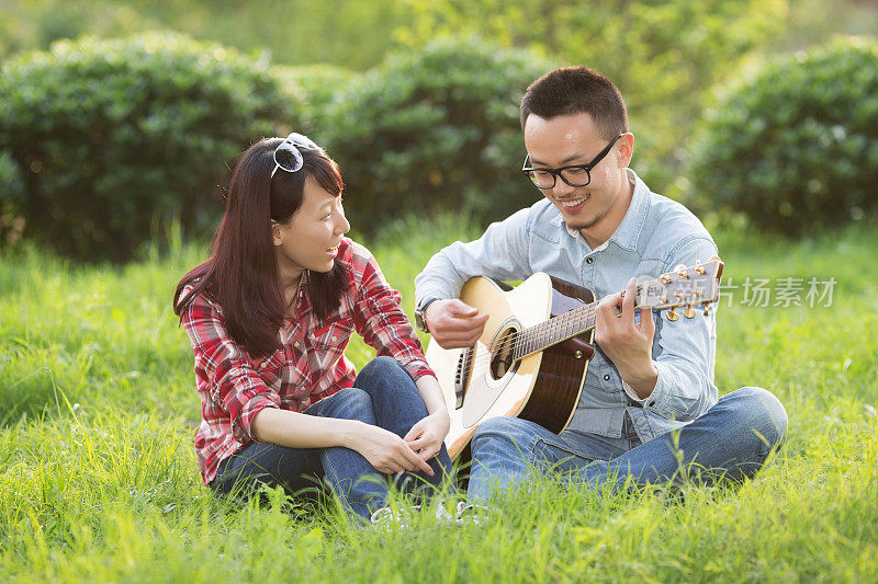 一对年轻夫妇在公园里弹吉他