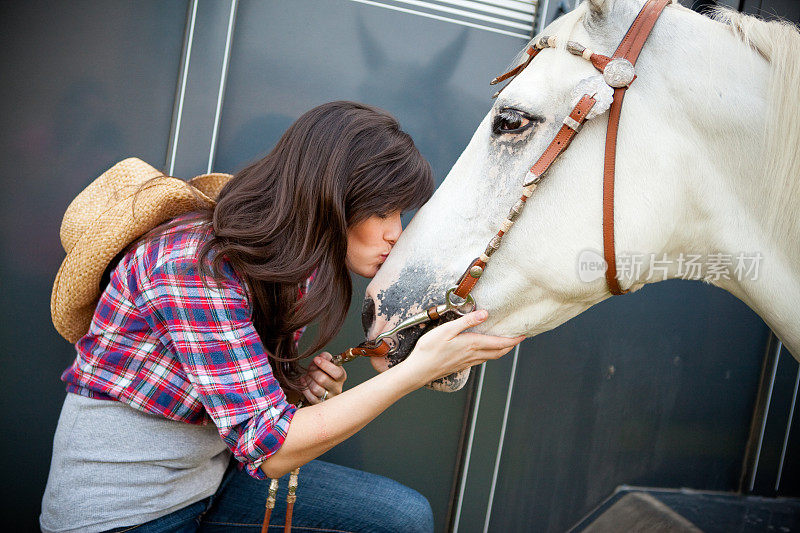 年轻的女牛仔给她的白马一个吻