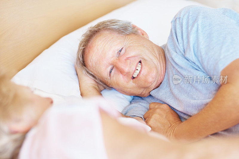 一个快乐的老人躺在床上他的妻子旁边
