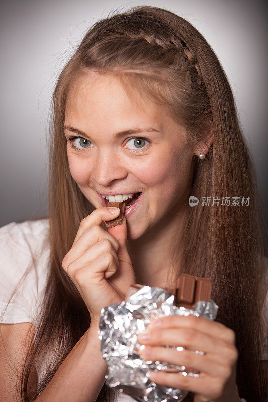 微笑的年轻女子在吃锡箔巧克力