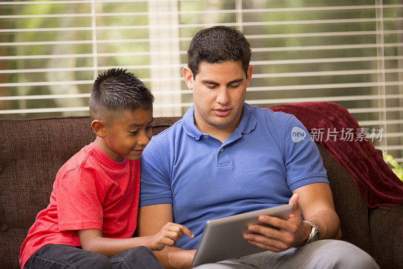 西班牙裔父亲和孩子在数字平板电脑上学习、玩耍。首页