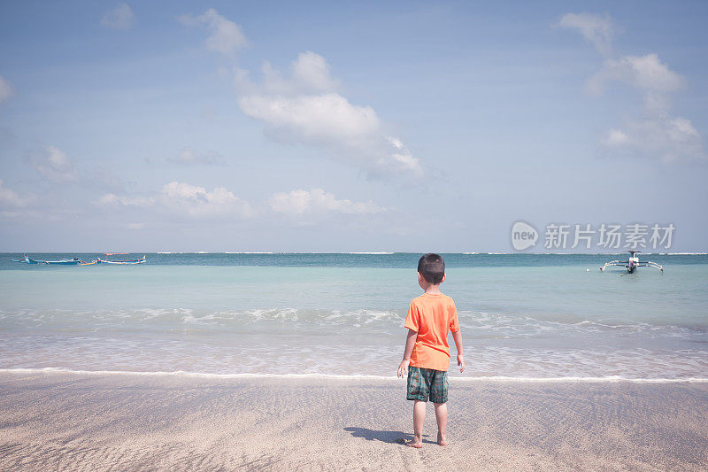 小男孩在海滩上看海浪