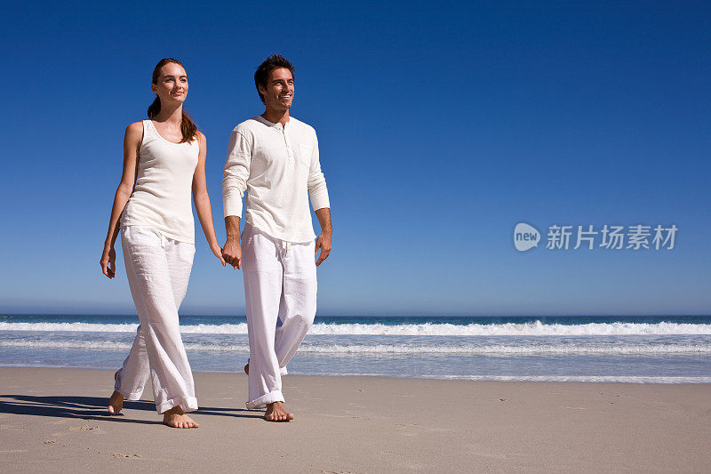 一对浪漫的年轻情侣在海滩上散步