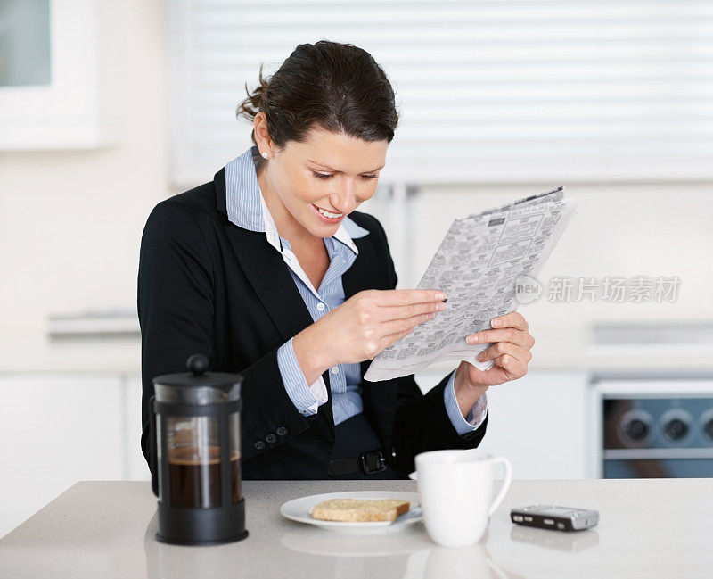 微笑的女商人一边吃早餐一边看报纸